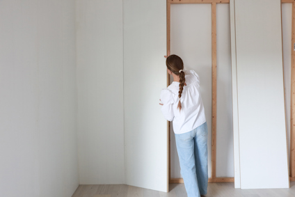 En person med flätat hår installerar vita paneler på en träram i ett rum.