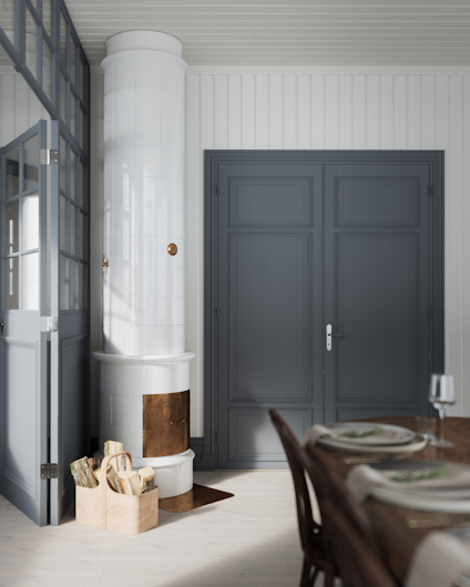 Vit kakelugn vid en grå dörr, vedkorg bredvid och dukat matbord i förgrunden.