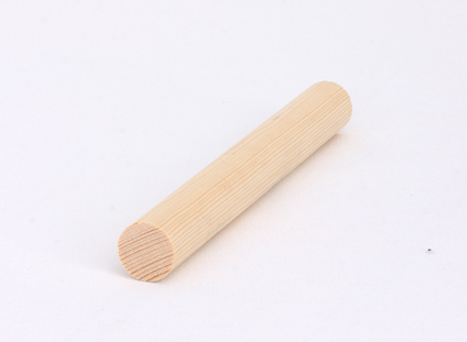 Trärundstav av ljust trä, liggande på en vit yta.