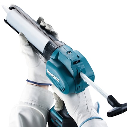 En person i vita handskar håller i en blå och vit fogpistol märkt "Makita".