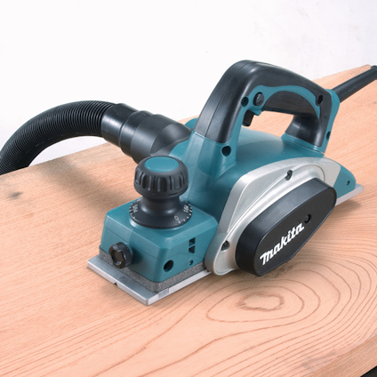 Elektrisk hyvel med märket "Makita" på sidan, ansluten till ett dammsugarrör.