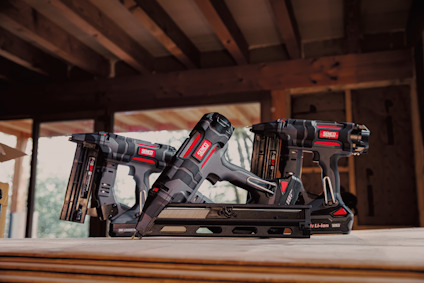 Verktyg med märket "Senco" är placerade på ett träbord i en konstruktion med synliga träbalkar.