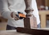 Person slipar träbit med orange slipblock märkt Bosch.