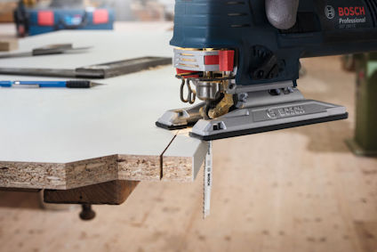 Sticksåg från Bosch skär genom en tjock träplatta i en verkstadsmiljö.