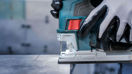 Sticksåg från Bosch, använd av person med handskar, skär genom en skiva.