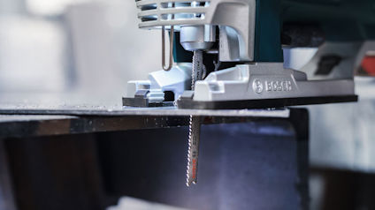 Sticksåg skär genom metall med sågtandat blad, märkning "Bosch" synlig på verktyget.