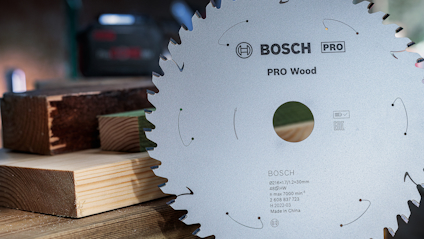 Cirkelsågklinga med text: "Bosch PRO Wood". Bakgrund med träplankor.