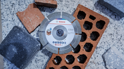 Diamantklinga från Bosch omgiven av tegelstenar och betongblock på granitbakgrund.